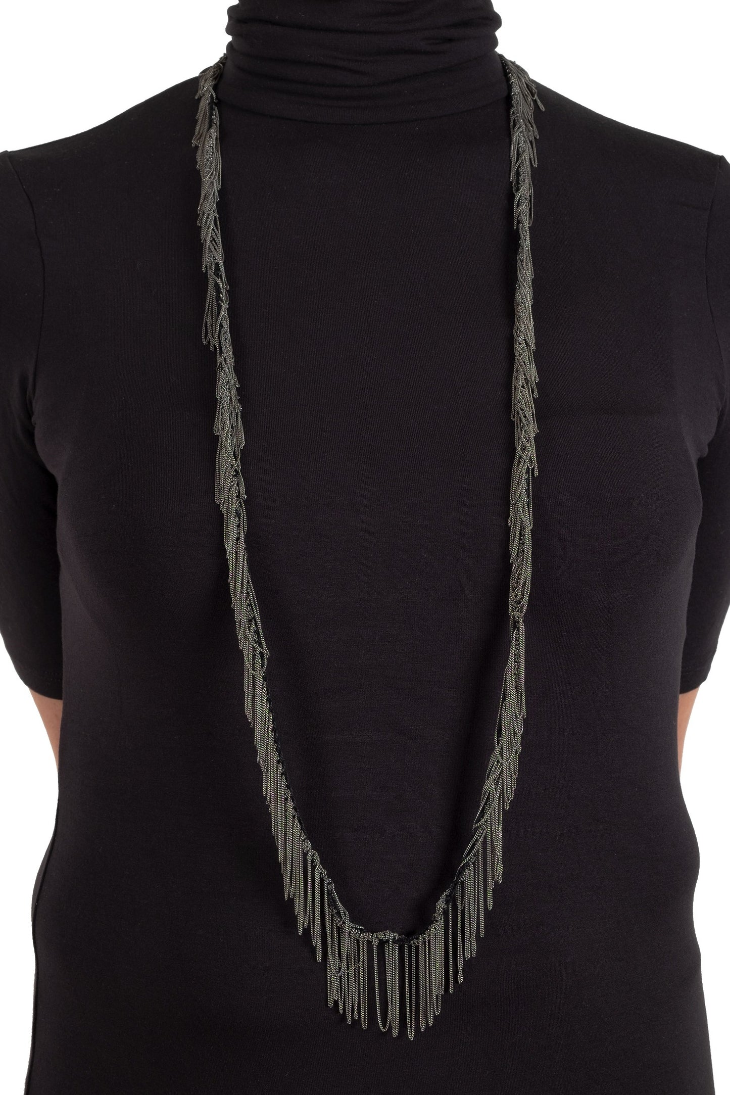 Person wearing a black turtleneck with a long gray fringe necklace.