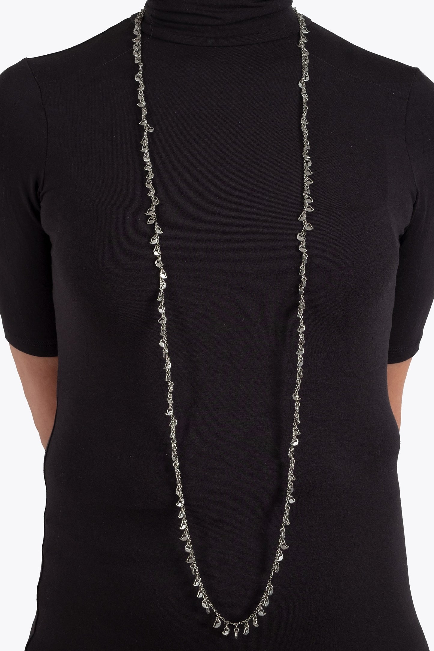 Person wearing a long, thin necklace against a plain background