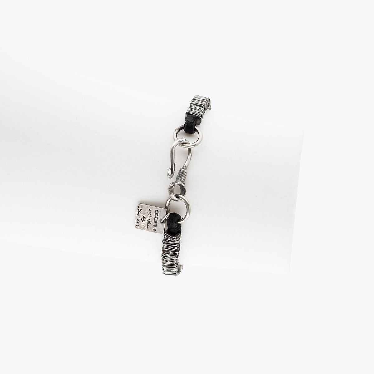 Silver charm with text on a white background