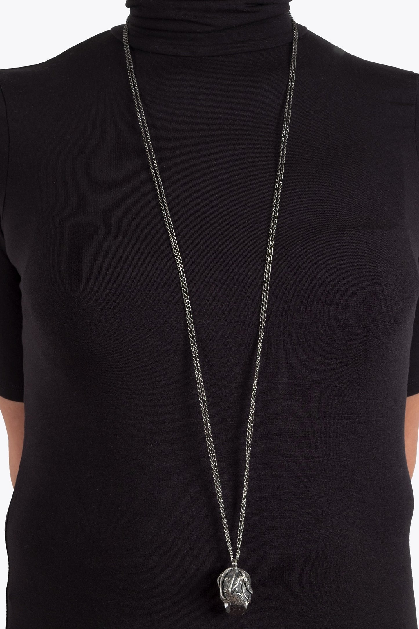 Long necklace with a pendant on a black turtleneck