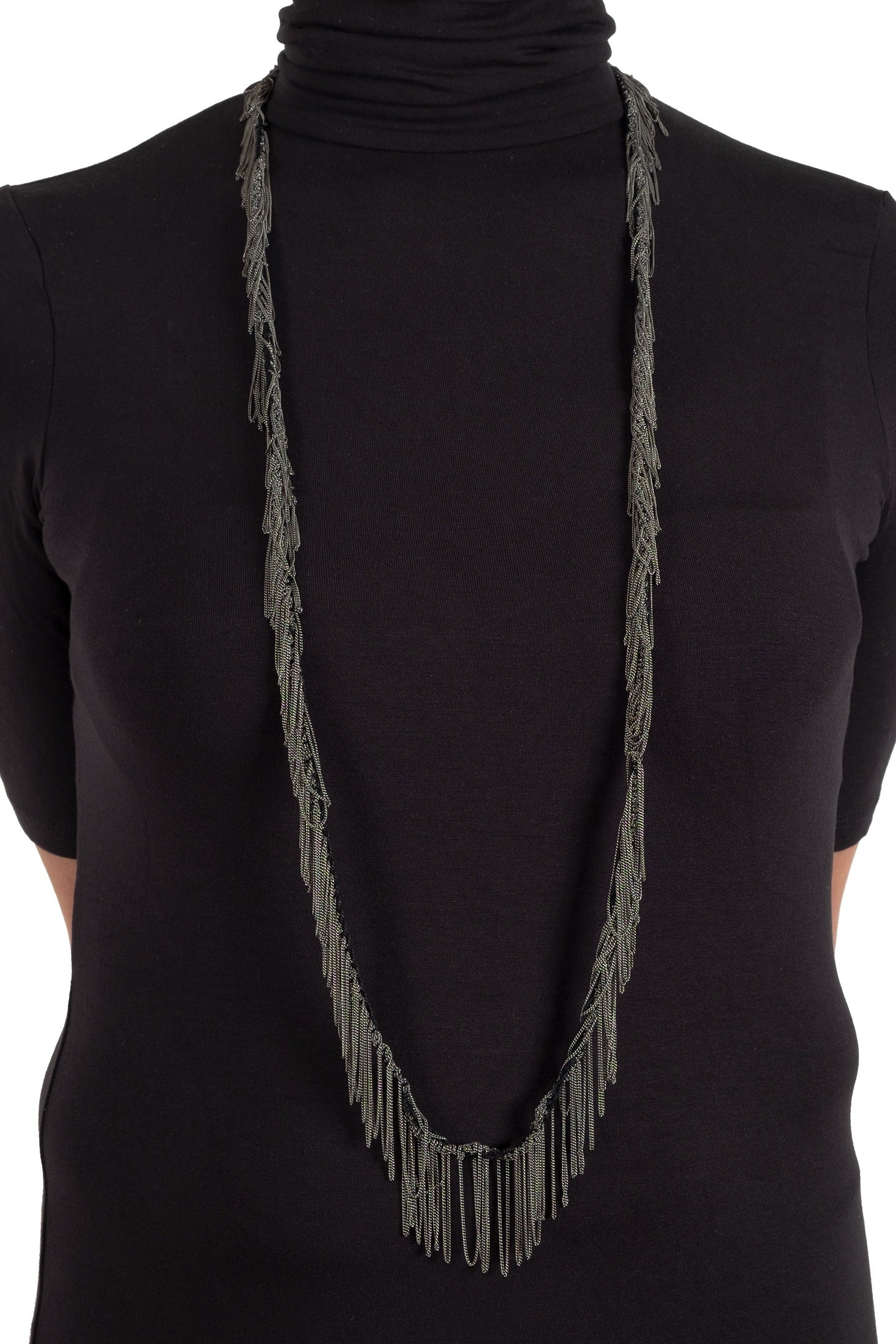 Person wearing a black turtleneck with a long gray fringe necklace.