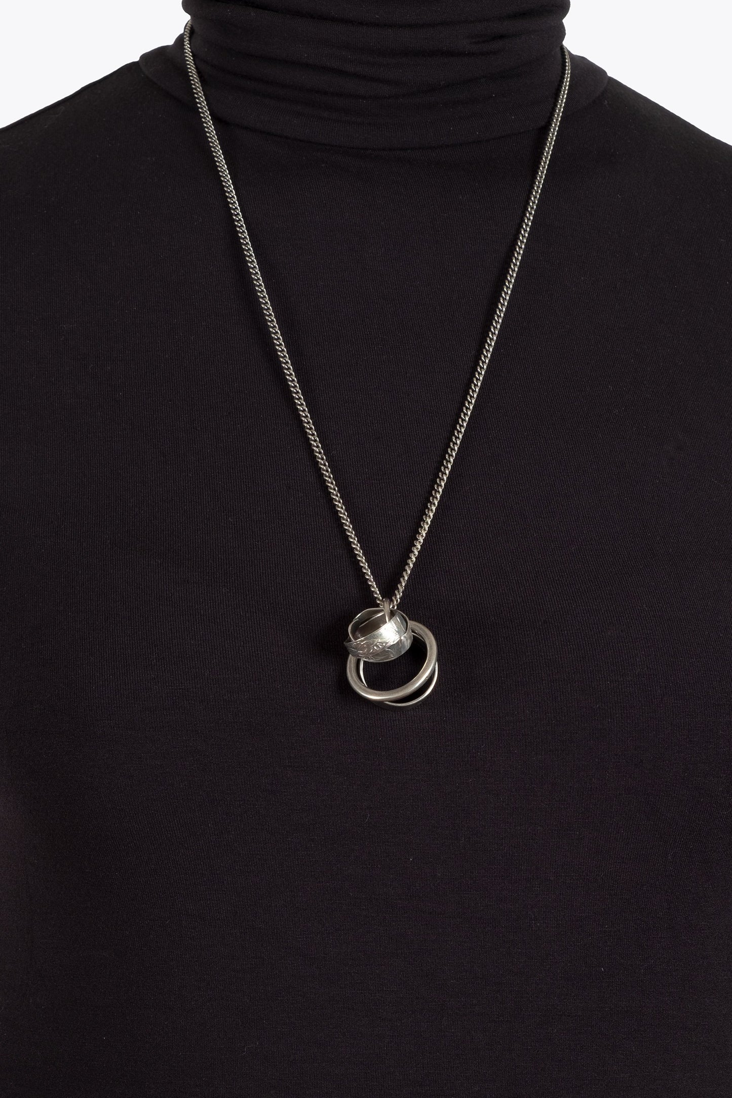Silver necklace with a pendant on a black turtleneck