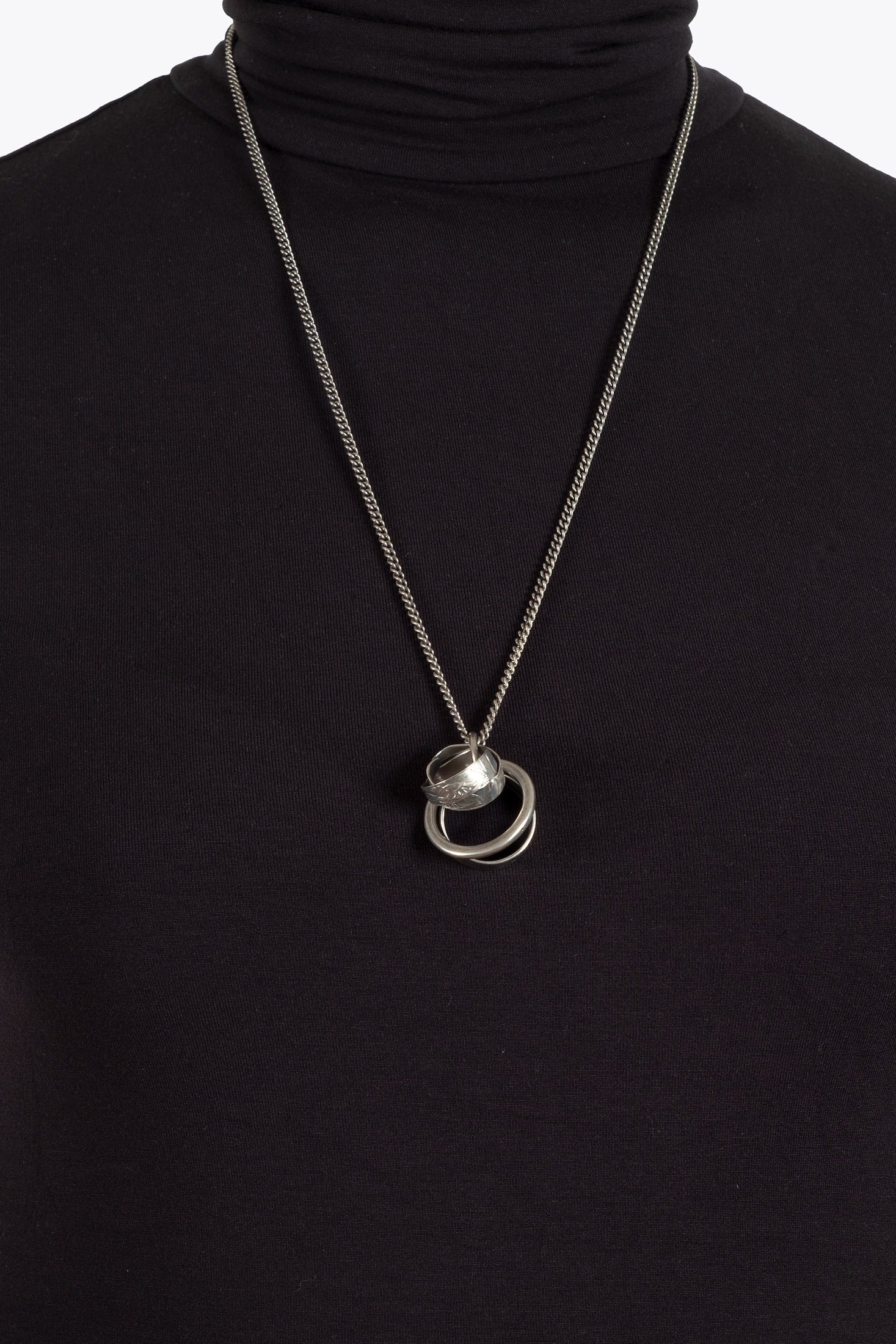 Silver necklace with a pendant on a black turtleneck
